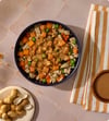 Chicken Peanut Satay bowl of fresh dog food topped with peanut butter drizzle, peas, carrots and sweet potato